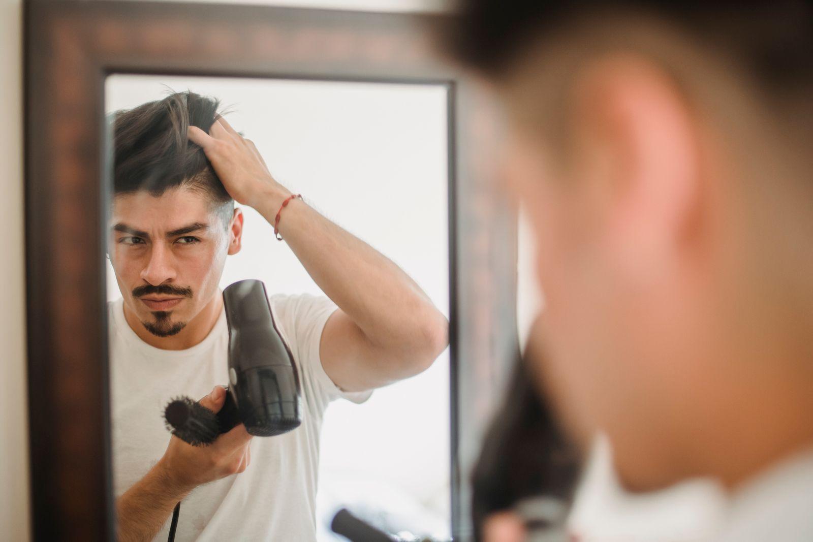 Man examining his hairline and thinning hair in a mirror